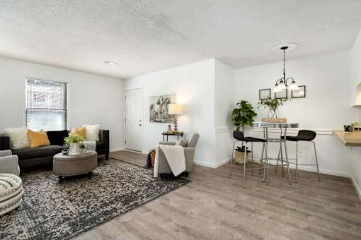A living room with a black couch, a grey ottoman, a white table, and a rug.