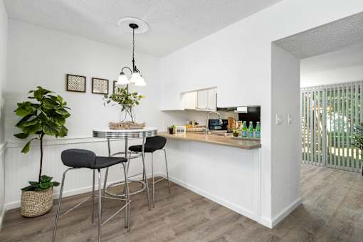 A kitchen with a bar area and a dining table with chairs.