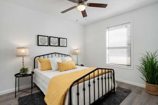 A bedroom with a bed, nightstand, and a ceiling fan.