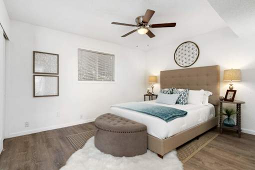 A bedroom with a large bed, a round mirror, and a ceiling fan.