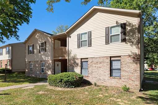 A two-story residential building with a brick base and siding on the upper level.
