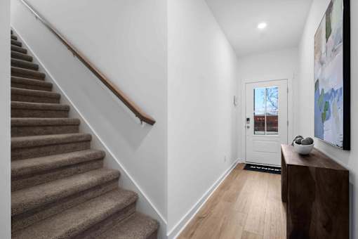 A hallway with a staircase and a door.