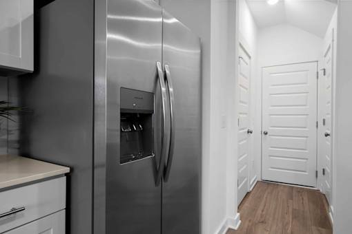 A stainless steel refrigerator in a kitchen with white cabinets.