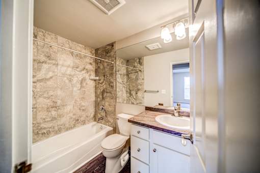 Tiled Bathroom with Tub and White Cabinets