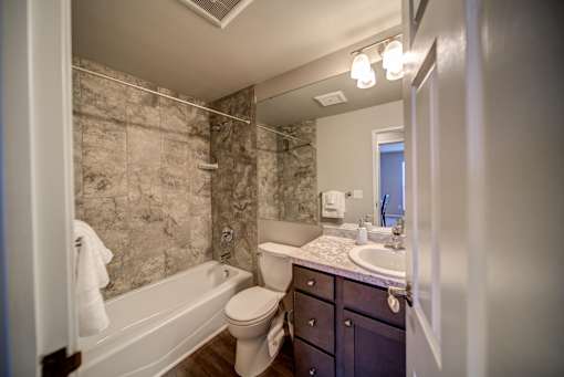 Tiled Bathroom with Tub and Dark Cabinets