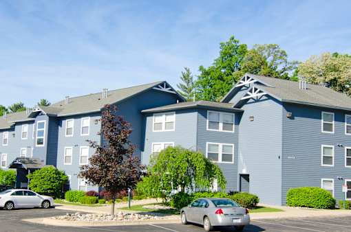 a blue apartment building with cars parked in front of it