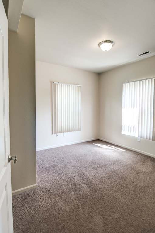 an empty living room with two windows and a door