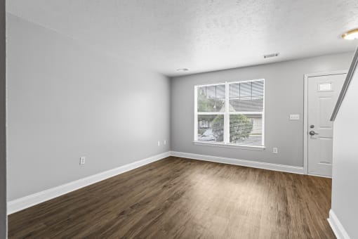 a bedroom with hardwood flooring and a large window