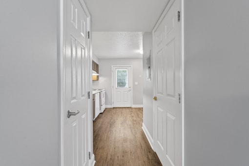 a hallway with two doors and a kitchen at the end of the hallway