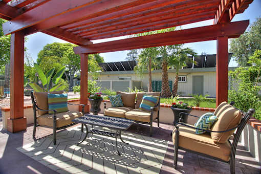 A patio with a red pergola and furniture.