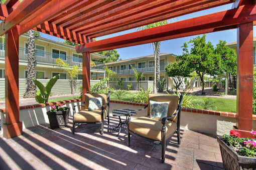 A patio with a red pergola and chairs.