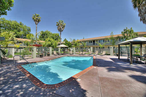 A pool surrounded by a fence and trees.