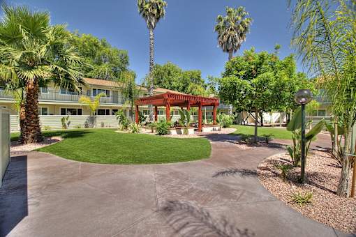 A red pavilion is in the middle of a courtyard with palm trees.