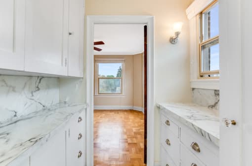 Kitchen with White Cabinets, Window, and Marble-look countertops and view into Living Area at Malloy Apartment Homes, Seattle, WA, 98105