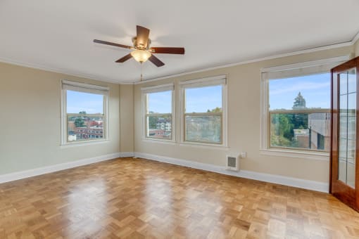 Wood Inspired Plank Flooring in Liivng Space Complete with Five Oversized Windows, A Ceiling Fan, and Views of Natural Scenery at Malloy Apartment Homes, Seattle, Washington