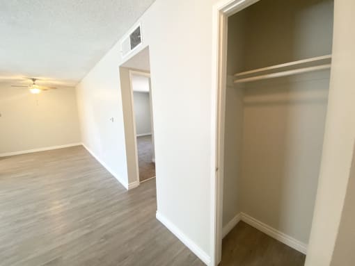 an empty living room with a closet and a hallway to a bedroom