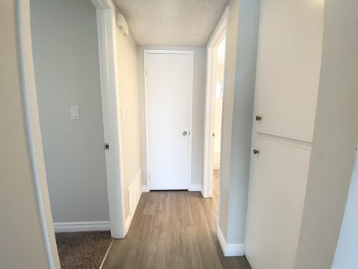 a hallway with wood floors and white walls and a closet