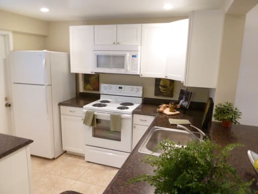 Apartment kitchen with white cabinets and dark countertop