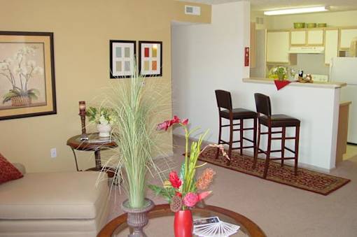 A living room with a couch, chairs, and a coffee table with flowers on it.