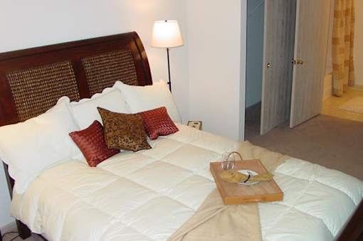 A bed with a white comforter and a wooden tray on it.