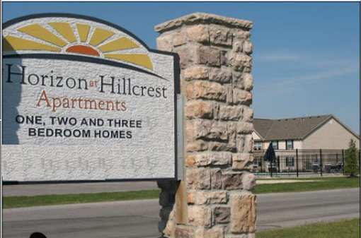 A sign for Horizon Hillcrest Apartments stands in front of a building.