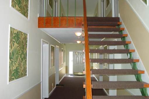 A staircase with a wooden handrail and a carpeted floor.