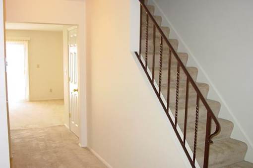A staircase with a metal railing and a carpeted floor.