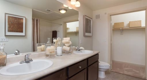 Master bathroom with floating vanities, quartz countertops, backlit vanity mirror, walk-in shower with Euro shower door and quartz-topped bench seat at The Pradera, Richardson, TX