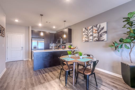 a dining area with a table and chairs and a kitchen in the background  at EdgeWater at City Center, Lenexa, 66219