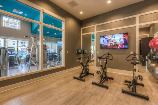 the gym with stationary bikes and a tv  at EdgeWater at City Center, Lenexa