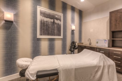 a room with a massage bed and a painting on the wall  at EdgeWater at City Center, Lenexa, KS