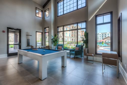 a pool table in the clubhouse with floor to ceiling windows  at EdgeWater at City Center, Lenexa