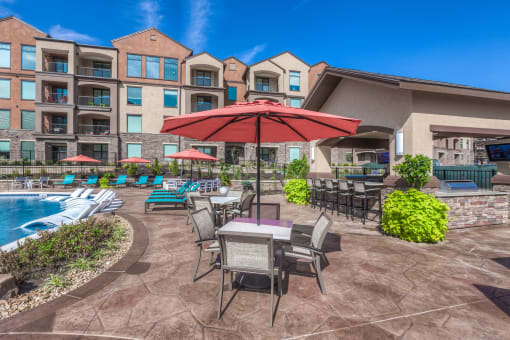a patio with a table and chairs and a pool in front of a building  at EdgeWater at City Center, Lenexa, KS