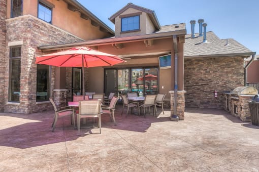 a patio with a grill and tables with umbrellas  at EdgeWater at City Center, Lenexa, KS