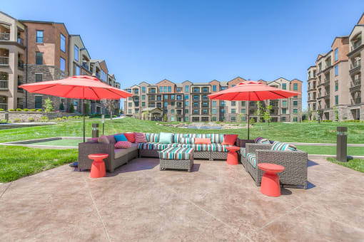an outdoor lounge area with umbrellas and apartments in background  at EdgeWater at City Center, Lenexa, 66219