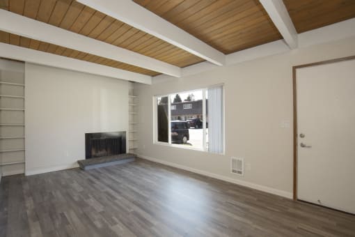 Apartment Interior with Overhead Exposed Ceiling Beams, Plank Flooring, and Fireplace with Large Windows at Woodlake Townhomes, Edmonds, WA