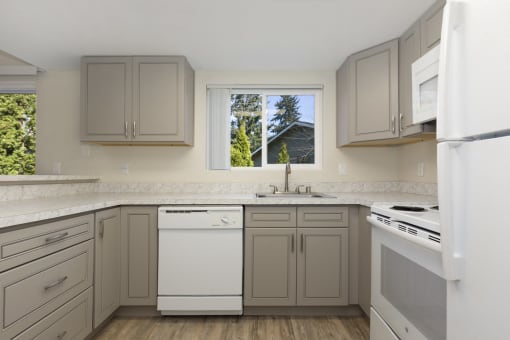 Renovated Kitchen with Grey Cabinets, Plank Flooring, and White Appliances at Woodlake Townhomes, Washington