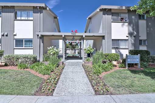 The image shows a pathway leading to a building with a sign that reads