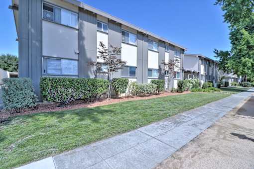 Apartment building with green bushes in front.