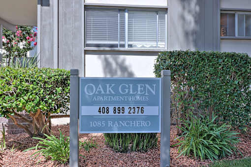 A sign for Oak Glen Apartment Homes stands in front of a building.