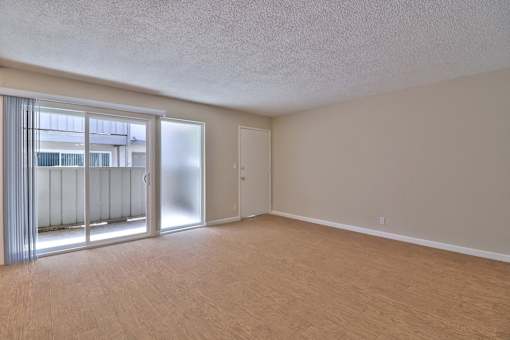 A room with a sliding glass door and a wooden floor.