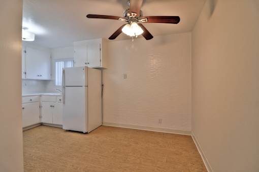 A room with a ceiling fan and a refrigerator.