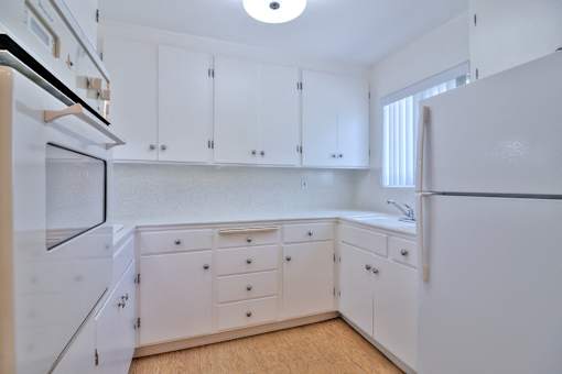 A white kitchen with wooden floors and white cabinets.