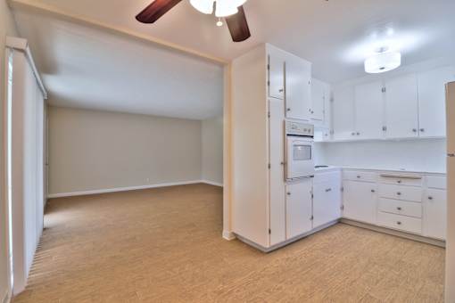 A kitchen with white cabinets and a wooden floor.