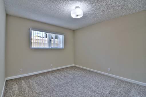 A room with a carpeted floor and a window with blinds.