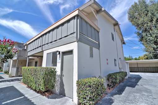 A white building with a grey roof and a grey door.