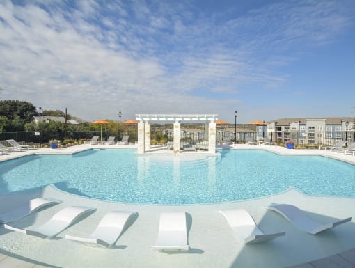 Bright and spacious pool deck with in-water loungers, comfortable seating, and a well-designed amenity space.