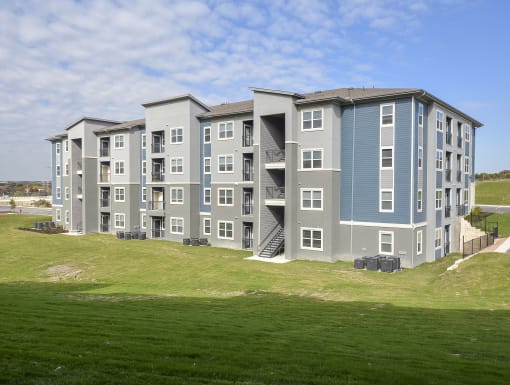 Contemporary residential building featuring multiple floors, spacious balconies, and landscaped surroundings.