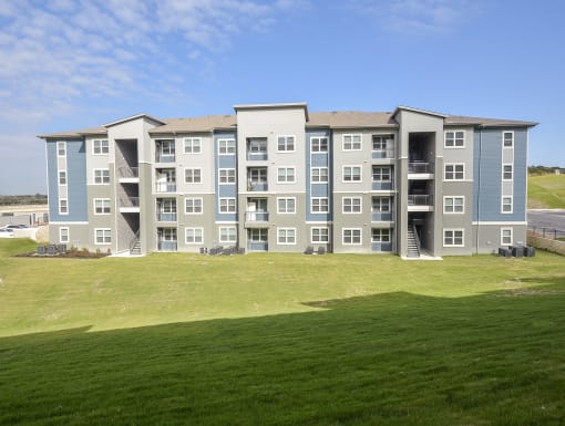 Modern apartment building exterior with clean architectural lines, private balconies, and open green space.