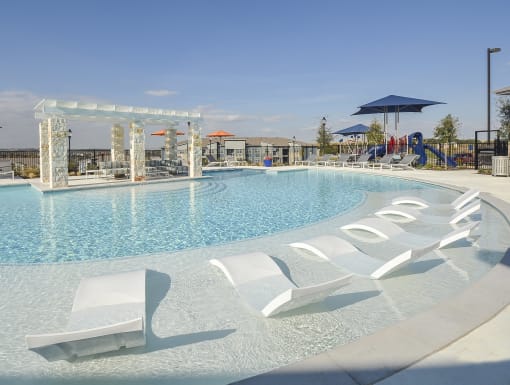 Bright and spacious pool deck with in-water loungers, comfortable seating, and a well-designed amenity space.